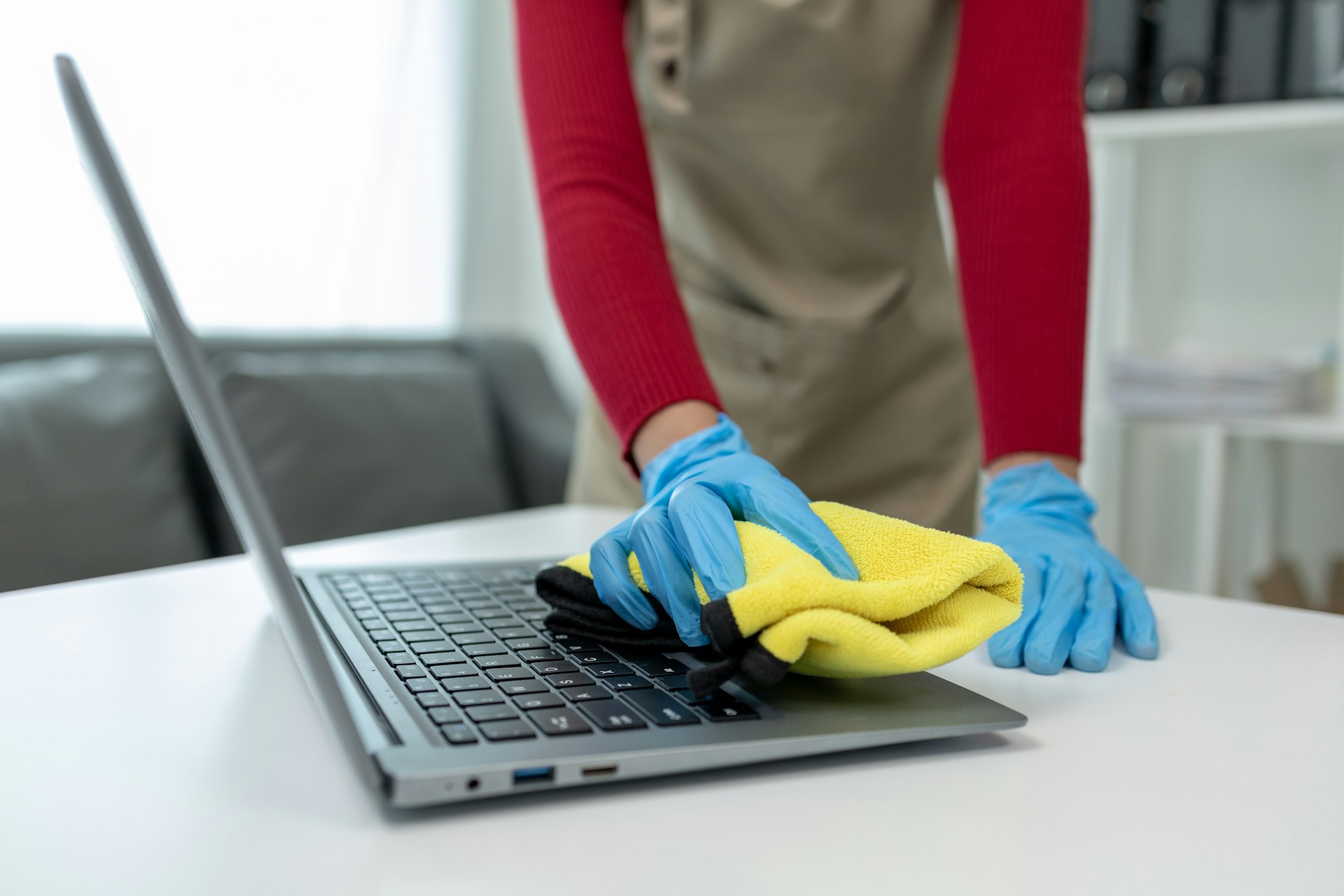 Janitor cleaning the office, Clean the notebook with a rag, wear gloves and wipe with a towel, Wear