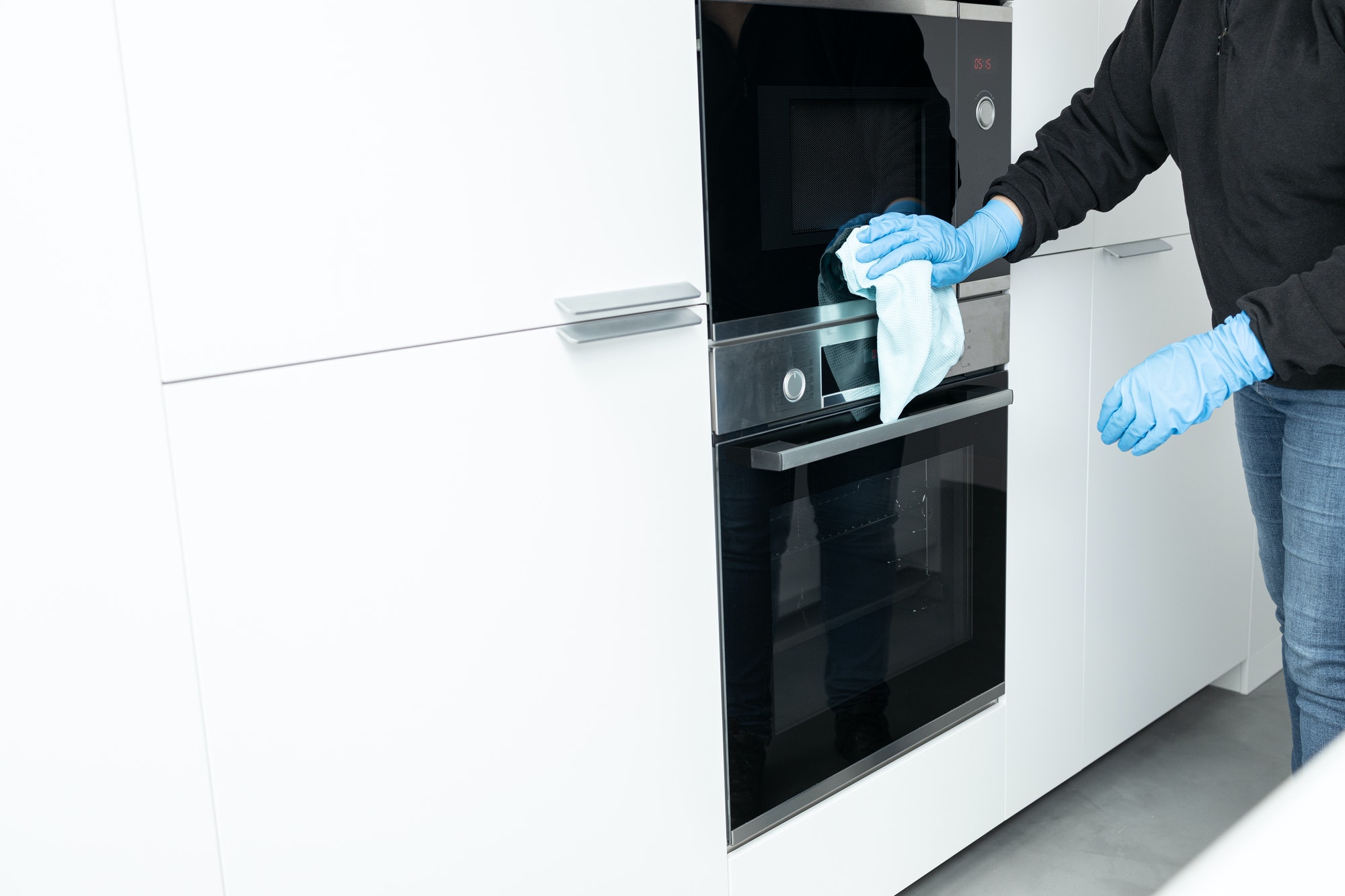 Woman cleaning a modern stainless steel appliances with rag