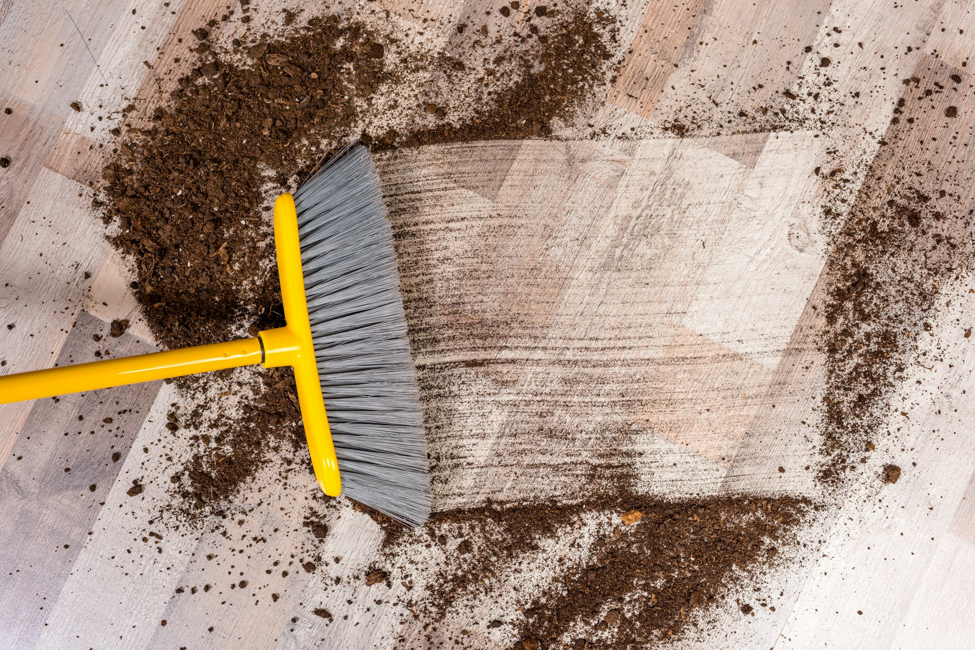 Close-up top view of broom sweeping floor with soil